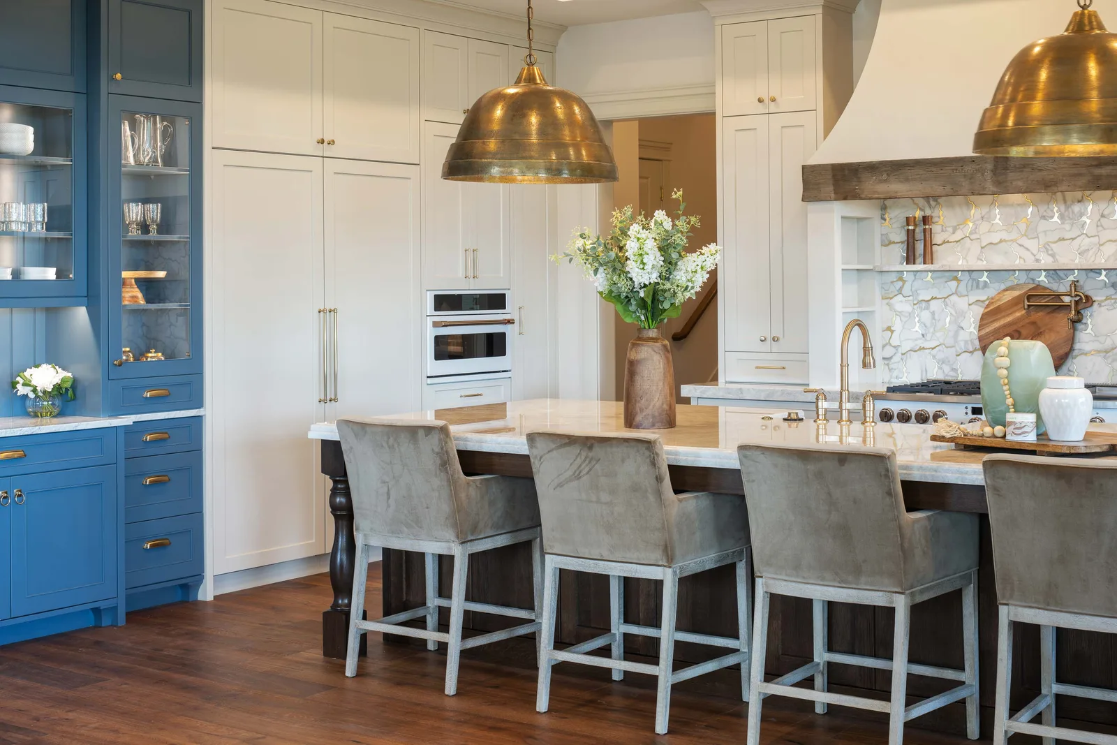 Blue cabinetry, brass, and a marble island