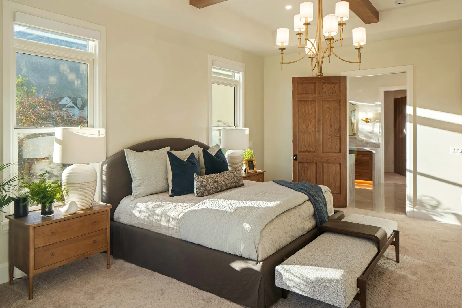 An upholstered bed framed by morning light